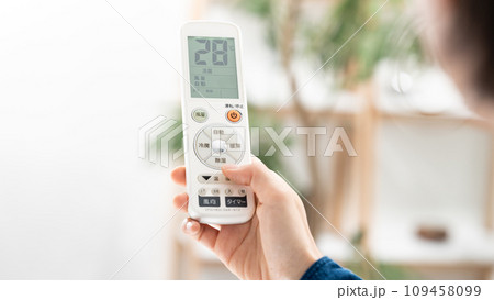 リモコンでエアコンの温度を確認する女性 109458099