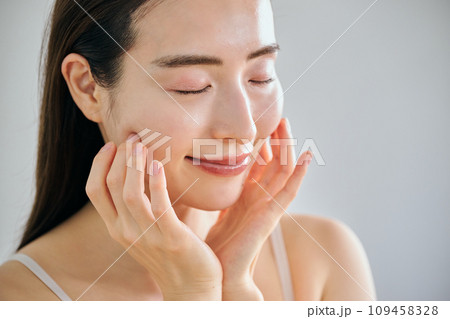 顔をマッサージして肌のお手入れをする30代女性 109458328