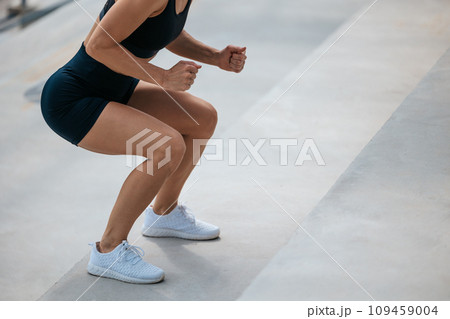 Woman in black sports shorts doing squats on the stairs Woman in black sports shorts doing squats on the stairs 109459004