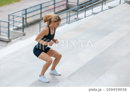 Blonde woman in sportswear jumping on the stairs 109459036