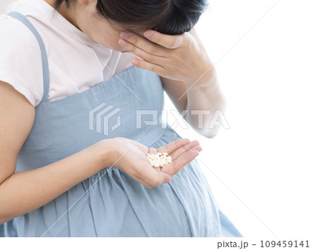 頭を抱えている女性が薬を持っているイメージ 頭を抱えている女性が薬を持っているイメージ 109459141