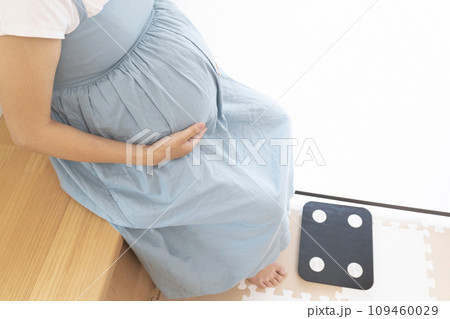 体重計の前に座る妊婦女性 体重計の前に座る妊婦女性 109460029