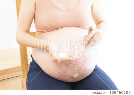 妊娠線ができたお腹にクリームを塗る女性の手と臨月のお腹 妊娠線ができたお腹にクリームを塗る女性の手と臨月のお腹 109460109
