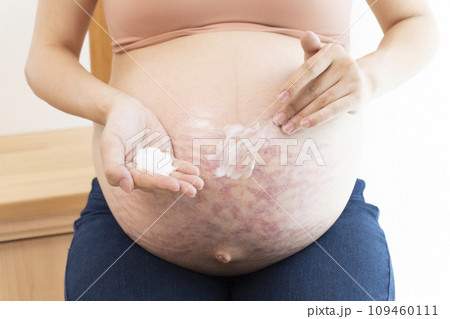 妊娠線ができたお腹にクリームを塗る女性の手と臨月のお腹 妊娠線ができたお腹にクリームを塗る女性の手と臨月のお腹 109460111