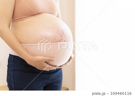 臨月の妊婦女性のお腹と腹帯 109460116