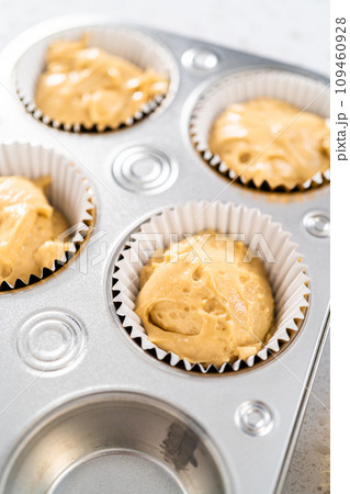 Scooping cupcake batter with a dough scoop into cupcake foil liners to bake  gingerbread cupcakes Stock Photo - Alamy