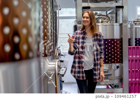 Winery worker woman walk and check the process of the machine in the modern factory with happiness. Winery worker woman walk and check the process of the machine in the modern factory with happiness. 109461257