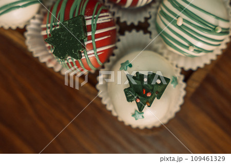 Rum balls of different colors decorated with chocolate in the shape of Christmas tree decorations Rum balls of different colors decorated with chocolate in the shape of Christmas tree decorations 109461329