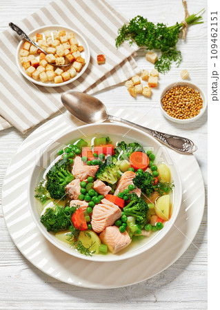 salmon, veggies and green herbs soup in bowl 109462151