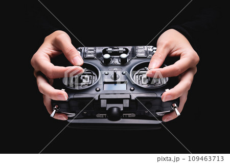 Remote control of FPV racing drone on black background in female hands, close-up 109463713