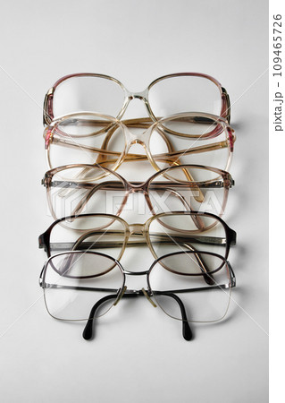 Old reading glasses stacked in a row on a white background 109465726