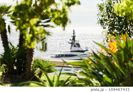 Monaco, Monte Carlo, 27 September 2022 - top of huge luxury yacht through trees and flowers at sunny day, the famous motorboat exhibition in the principality Monaco, Monte Carlo, 27 September 2022 - top of huge luxury yacht through trees and flowers at sunny day, the famous motorboat exhibition in the principality 109467435