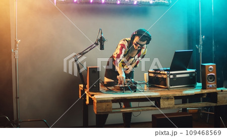 Sleepy dj woman yawning and trying to mix records at party, drinking coffee to get some energy for great techno performance at nightclub. Artist feeling exhausted at stereo turntables. Handheld shot. Sleepy dj woman yawning and trying to mix records at party, drinking coffee to get some energy for great techno performance at nightclub. Artist feeling exhausted at stereo turntables. Handheld shot. 109468569