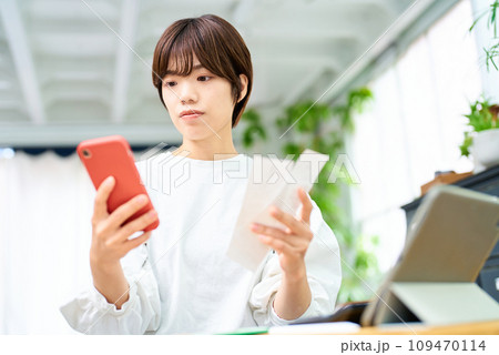 レシートとスマートフォンを手にする若い女性 レシートとスマートフォンを手にする若い女性 109470114