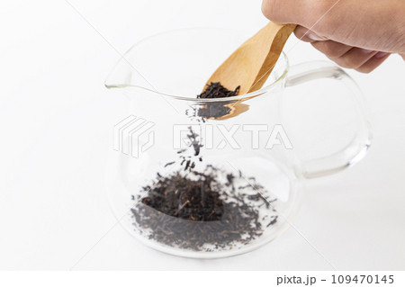 紅茶をティーポットに入れている手元　白バック 109470145