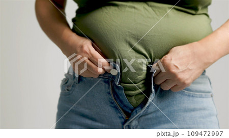 Fat woman zipping up trousers, excess belly fat, unhealthy lifestyle Fat woman zipping up trousers, excess belly fat, unhealthy lifestyle 109472997