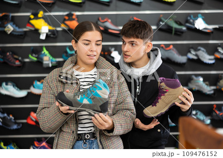 Couple examine view several item of winter comfortable trecking shoes Couple examine view several item of winter comfortable trecking shoes 109476152