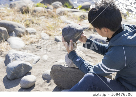 河原でロックバランシングをする男性 109476506