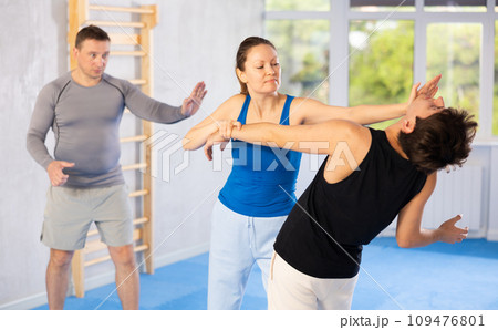 Woman practices blows to head of her attacking man during self-defense training under the guidance of trainer Woman practices blows to head of her attacking man during self-defense training under the guidance of trainer 109476801