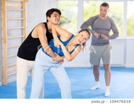 Guy and woman train to perform defense of strangling opponent, while learning self-defense Guy and woman train to perform defense of strangling opponent, while learning self-defense 109476838