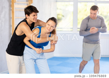 Guy and woman train to perform defense of strangling opponent, while learning self-defense Guy and woman train to perform defense of strangling opponent, while learning self-defense 109476869