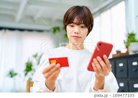 カードを持ってスマートフォンを操作する女性 カードを持ってスマートフォンを操作する女性 109477105
