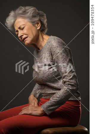 A senior woman experiencing severe back pain, holding her lower back in discomfort. AI Generated. Fictional person. 109478354