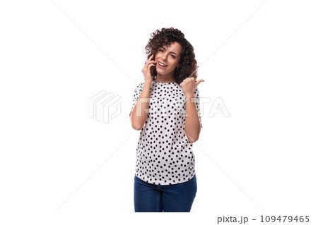 a slender young stylish woman with a curly haircut dressed in a blouse with polka dots speaks on the 109479465
