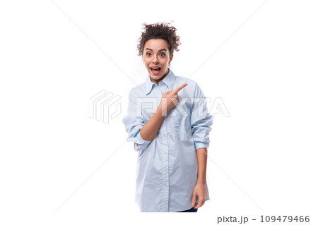 young surprised curly brunette secretary woman dressed in a light blue shirt on a white background 109479466