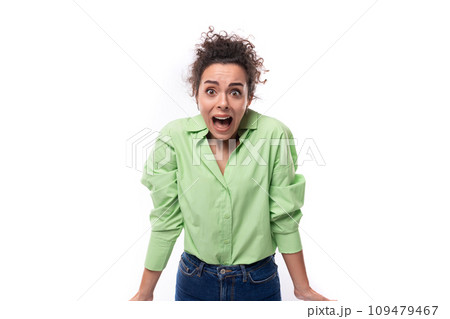 young brunette curly slender female model dressed in a light green shirt stands in confusion on a young brunette curly slender female model dressed in a light green shirt stands in confusion on a 109479467