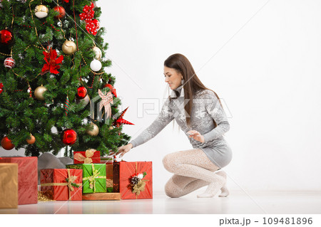Portrait of happy young woman christmas present boxes in front of christmas tree 109481896