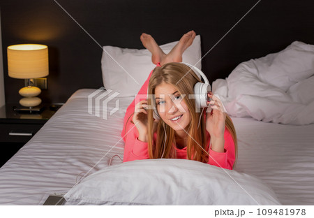 Young women listening to the music from smartphone on bed Young women listening to the music from smartphone on bed 109481978