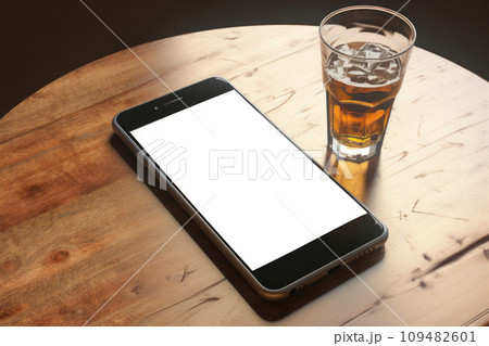 The mobile phone is on the table with a glass of whiskey 109482601