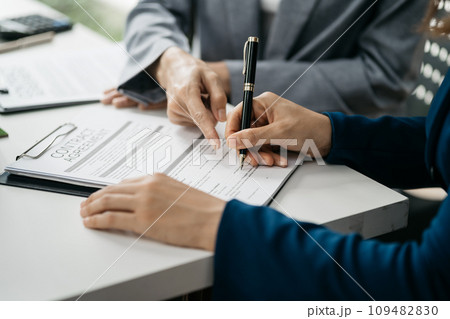 Real estate broker agent presenting and consult to customer to decision making sign insurance form agreement, home model, concerning mortgage loan offer in office. 109482830