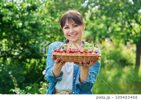 Happy woman with harvest of red ripe cherries in summer garden Happy woman with harvest of red ripe cherries in summer garden 109483468