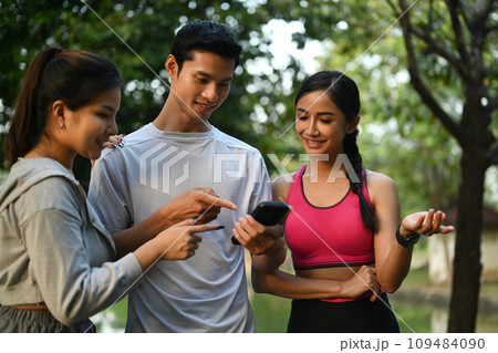 Smiling male and female sports people using a fitness app to monitor their progress after morning workout 109484090