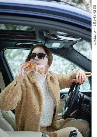 A woman is stuck in a car on Christmas Eve and drinks champagne while waiting for a tow truck. A woman is stuck in a car on Christmas Eve and drinks champagne while waiting for a tow truck. 109484288