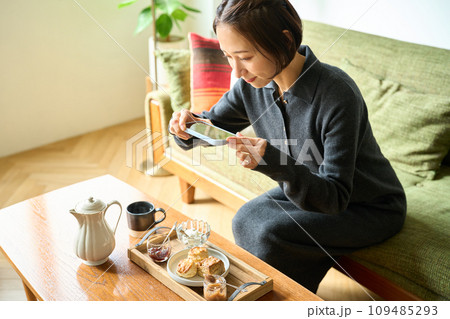 スマートフォンで焼き菓子(スコーン)を撮影する女性 スマートフォンで焼き菓子(スコーン)を撮影する女性 109485293