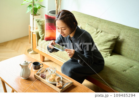スマートフォンで焼き菓子（スコーン）を撮影する女性 109485294