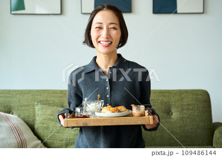 焼き菓子（スコーン）を手にもつ女性 109486144