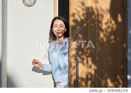 玄関の扉を開ける女性 109486259