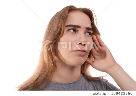 A blonde teenage girl of European appearance in a gray T-shirt is puzzled by solving a problem A blonde teenage girl of European appearance in a gray T-shirt is puzzled by solving a problem 109488266