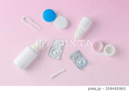 Contact lenses with container, solution bottle and accessories on pink background, top view 109488963