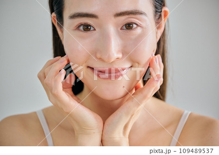 顔をマッサージして肌のお手入れをする30代女性 109489537