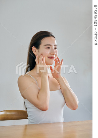 顔をマッサージして肌のお手入れをする30代女性 109489539