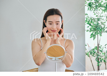 顔をマッサージして肌のお手入れをする30代女性 109489542