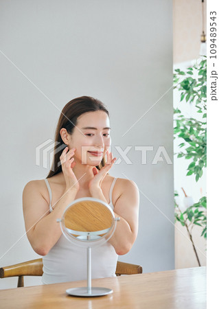 顔をマッサージして肌のお手入れをする30代女性 109489543