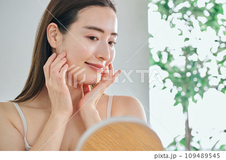 顔をマッサージして肌のお手入れをする30代女性 109489545