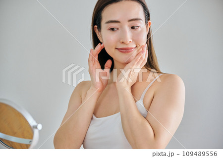 顔をマッサージして肌のお手入れをする30代女性 109489556