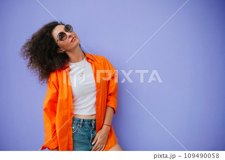 Bright and colorful. Stunning woman in shorts posing against violet wall 109490058